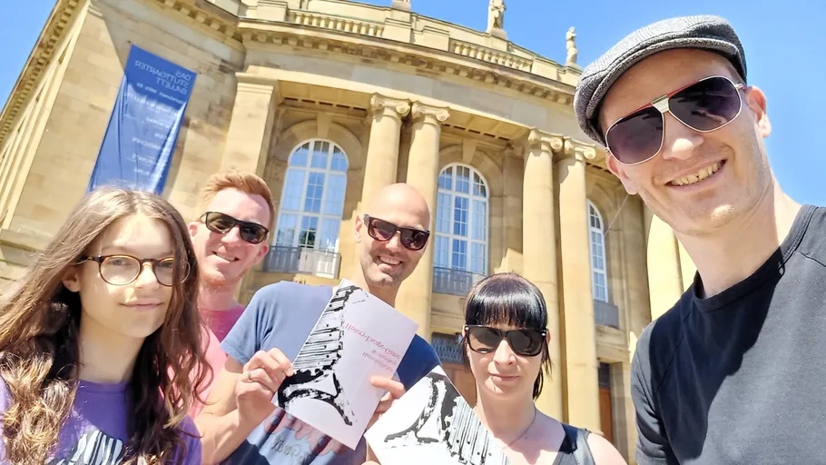 Gruppe von Menschen lächelt vor einem Gebäude.