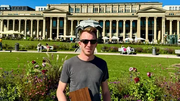 Person hält ein Buch in einer Gartenszene.