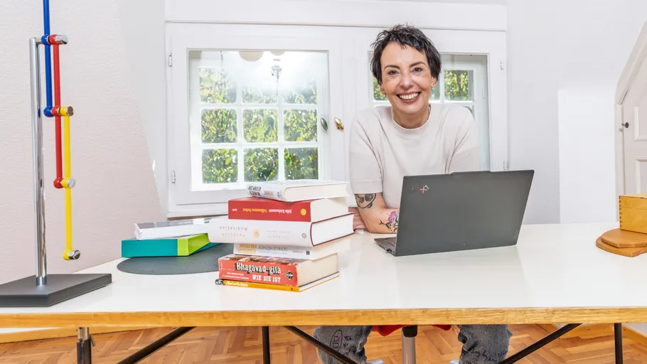 Person sitting at a desk with laptop and books.