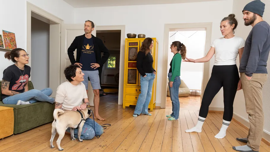 Seven people and a dog in a living room.