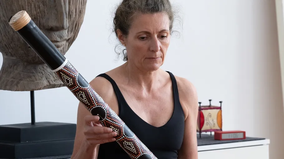 Frau hält ein verziertes Musikinstrument drinnen.