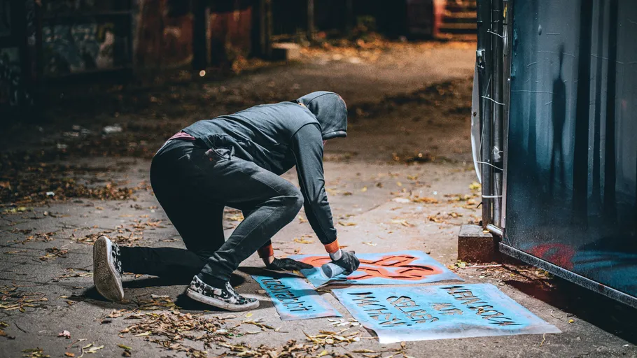Person spray painting street art at night.