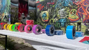 Bunte Klebebandrollen auf Tisch, Graffiti-Hintergrund.