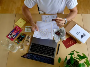 A person keeps chocolate and notes at the table.