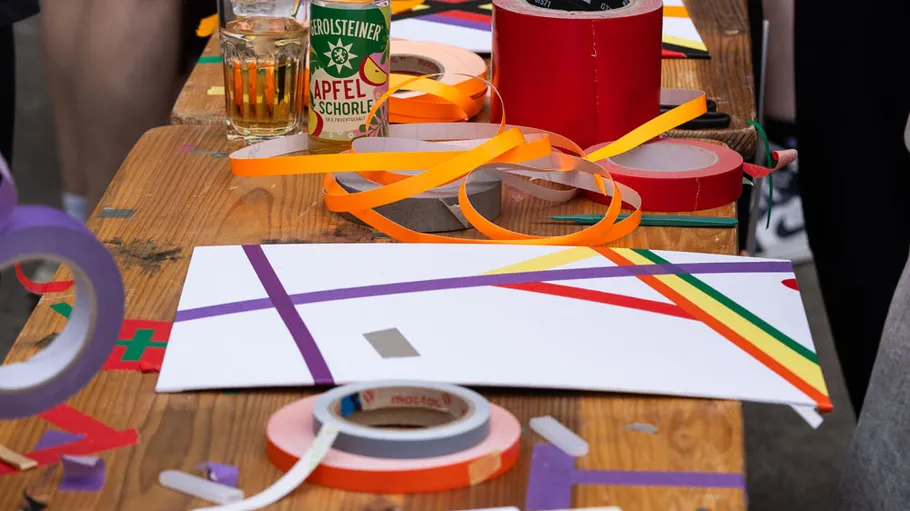 Kunsttisch mit buntem Klebeband und Getränken.