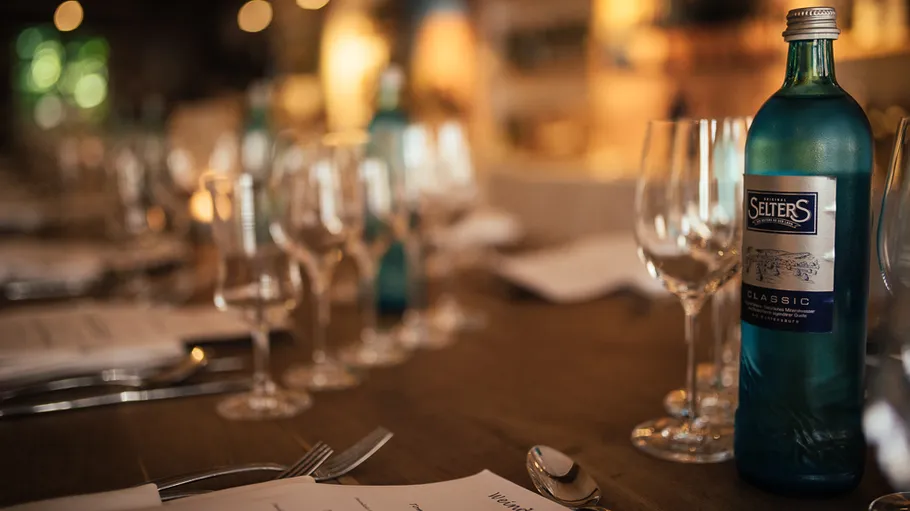 Blue bottle on elegantly set dining table.