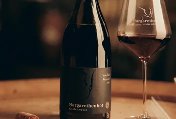 Weinflasche und Glas auf Holztisch.