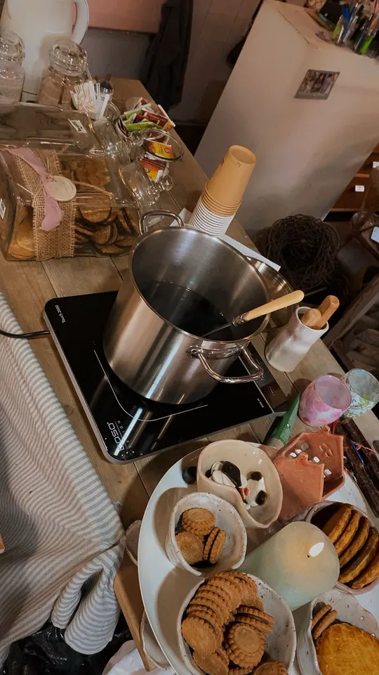 Induction stove with large pot, cookies, table setting.