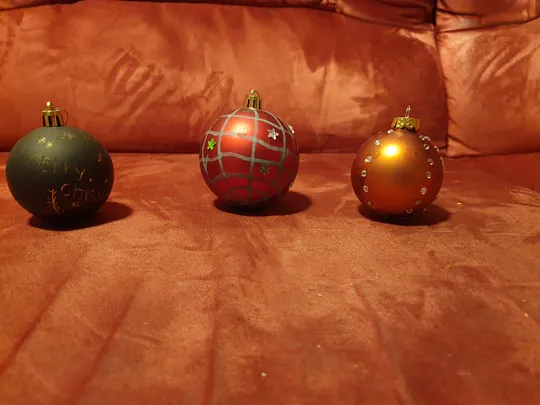 Drei Weihnachtskugeln auf einem Sofa.