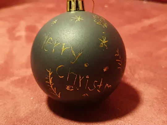 Schwarze Kugel mit handgeschriebener Weihnachtsbotschaft.