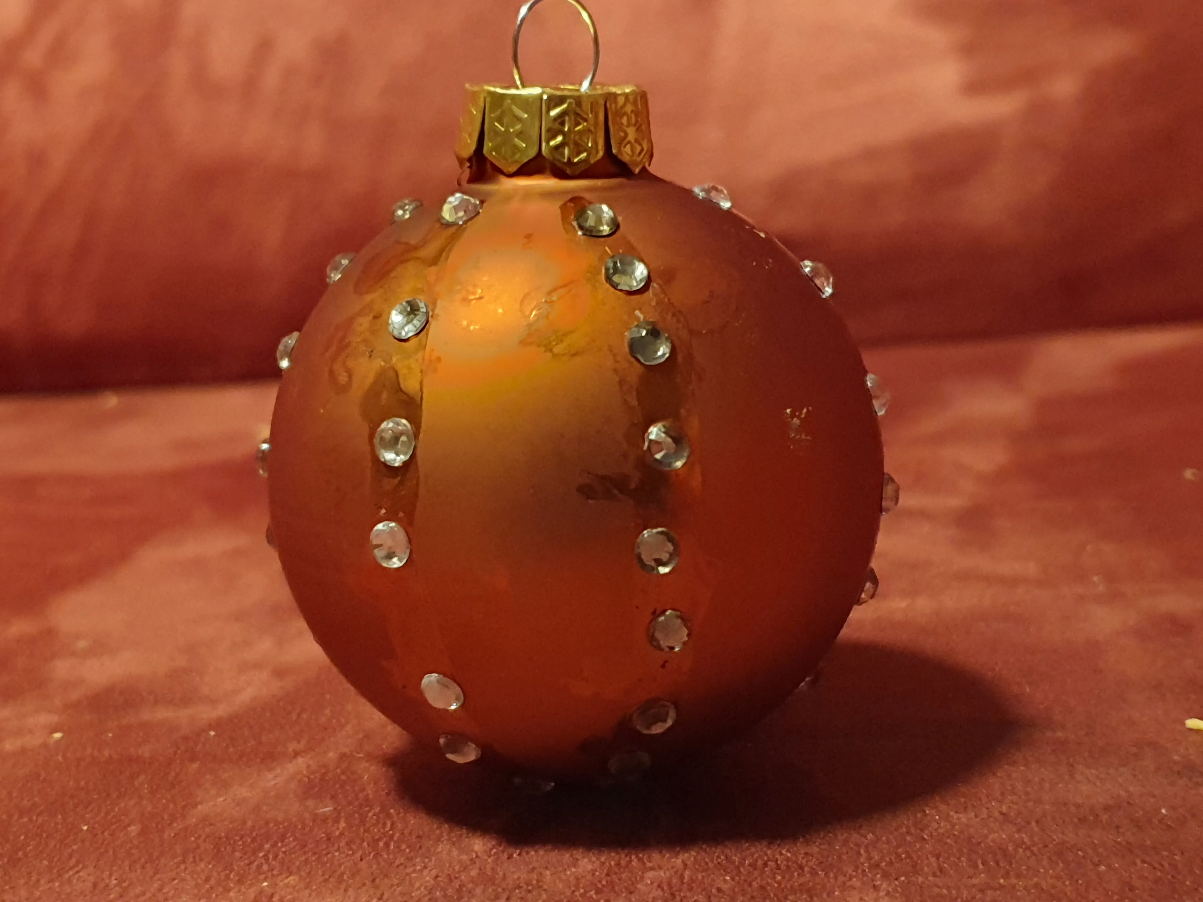 Orange ornament with rhinestones on a couch.