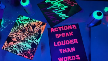 Sprühgemalte Leinwände mit Neonfarben auf einem Tisch.