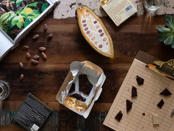 Cocoa beans and chocolate lie on a wooden table.