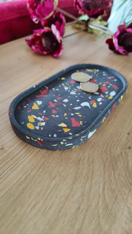 Coins on terrazzo tray with flowers nearby.