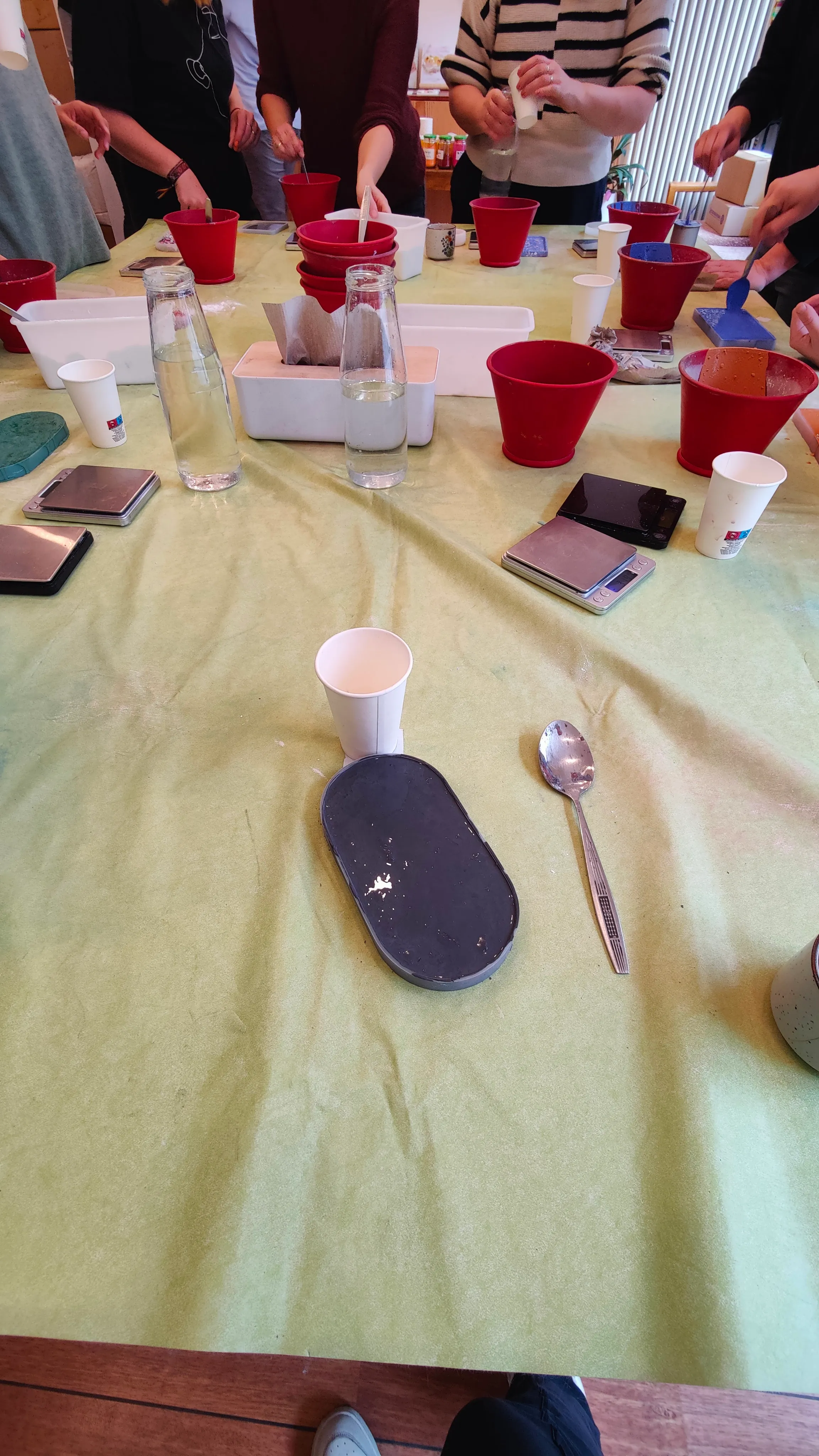 People mixing ingredients in red buckets on table.