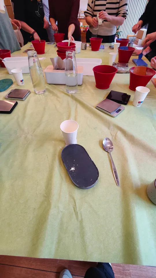 People mixing ingredients in red buckets on table.