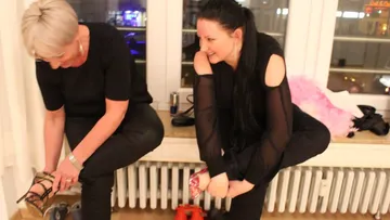Two women change shoes on radiator bench.