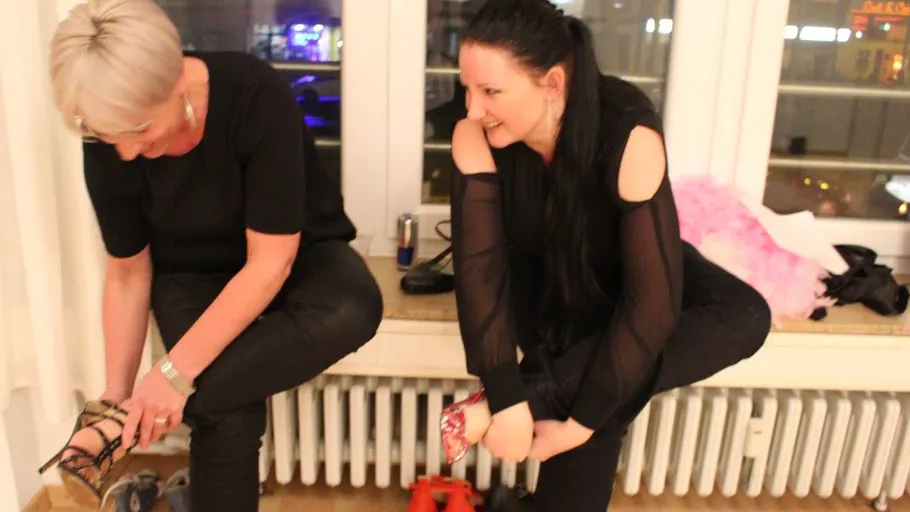 Two women change shoes on radiator bench.