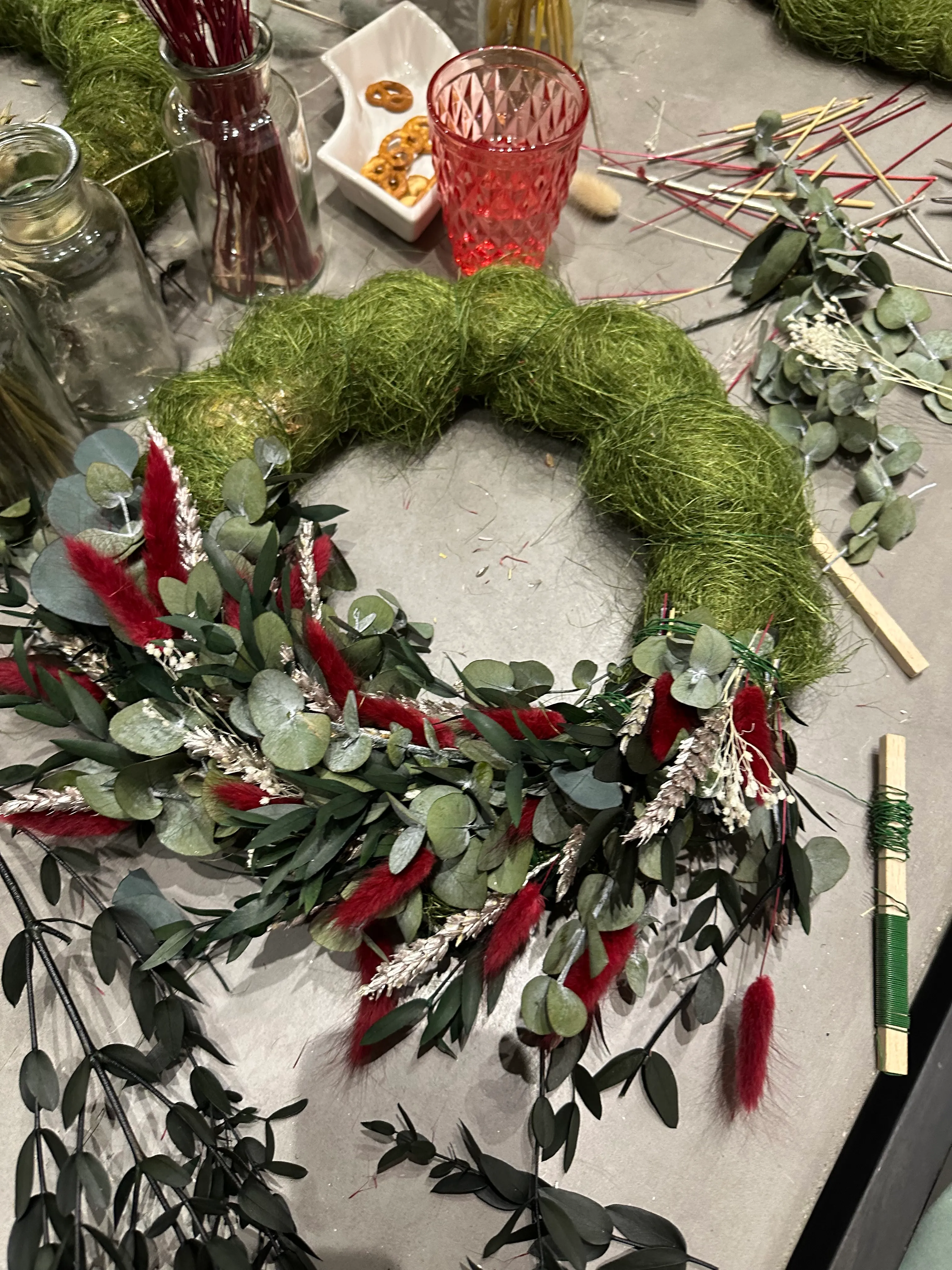 Dekorativer Kranzbau mit grünen und roten Akzenten.