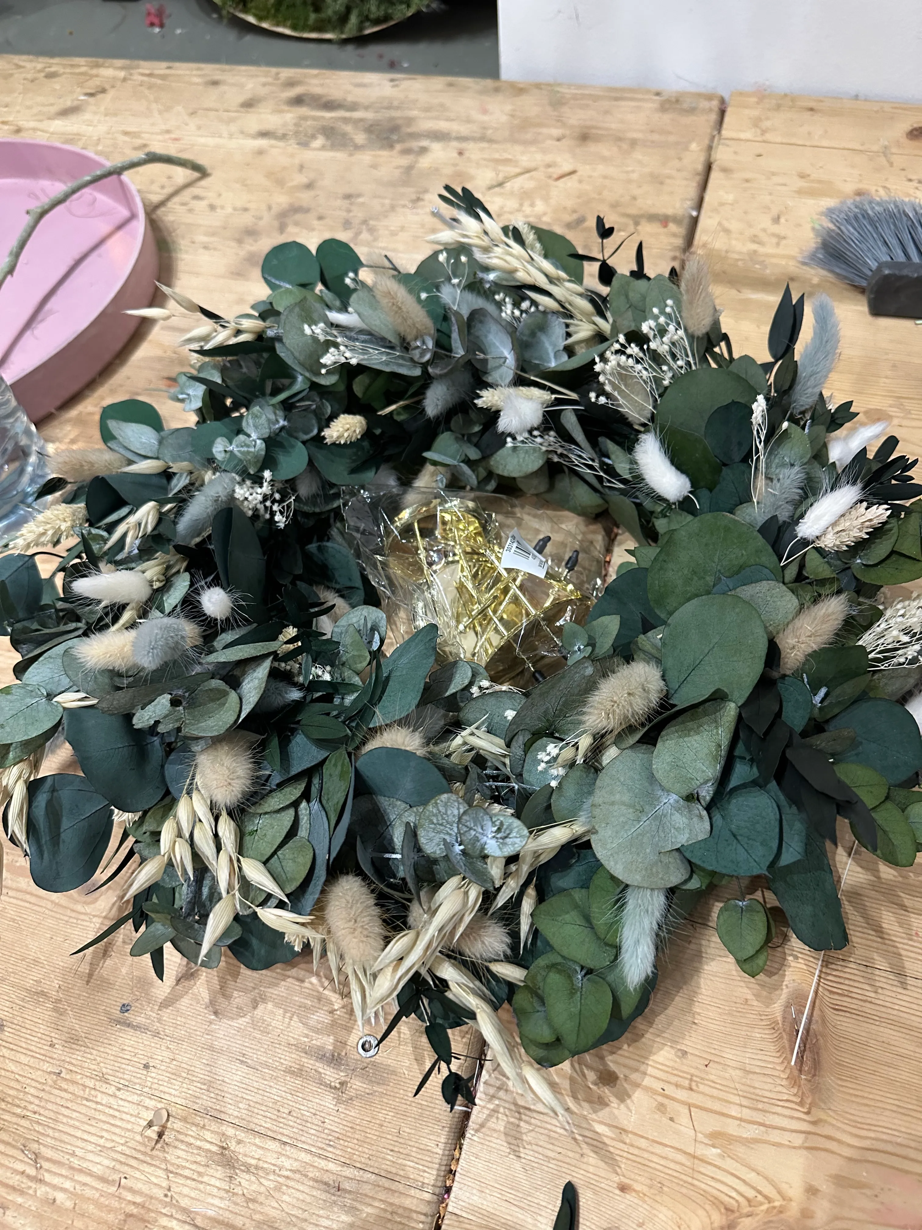 Kranz mit grünen Blättern auf Holztisch.