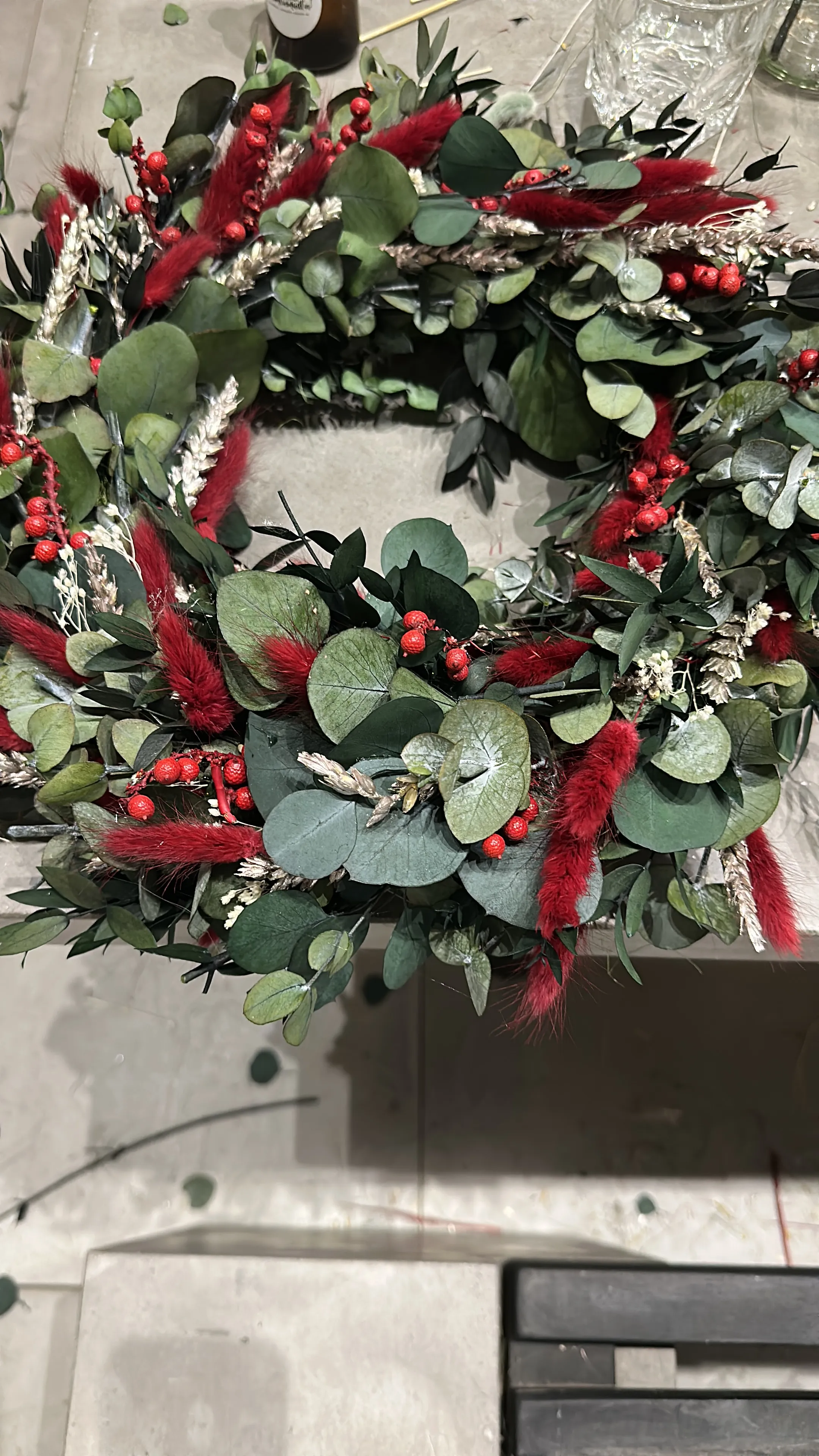 Dekorativer Kranz mit roten Beeren auf einem Tisch.