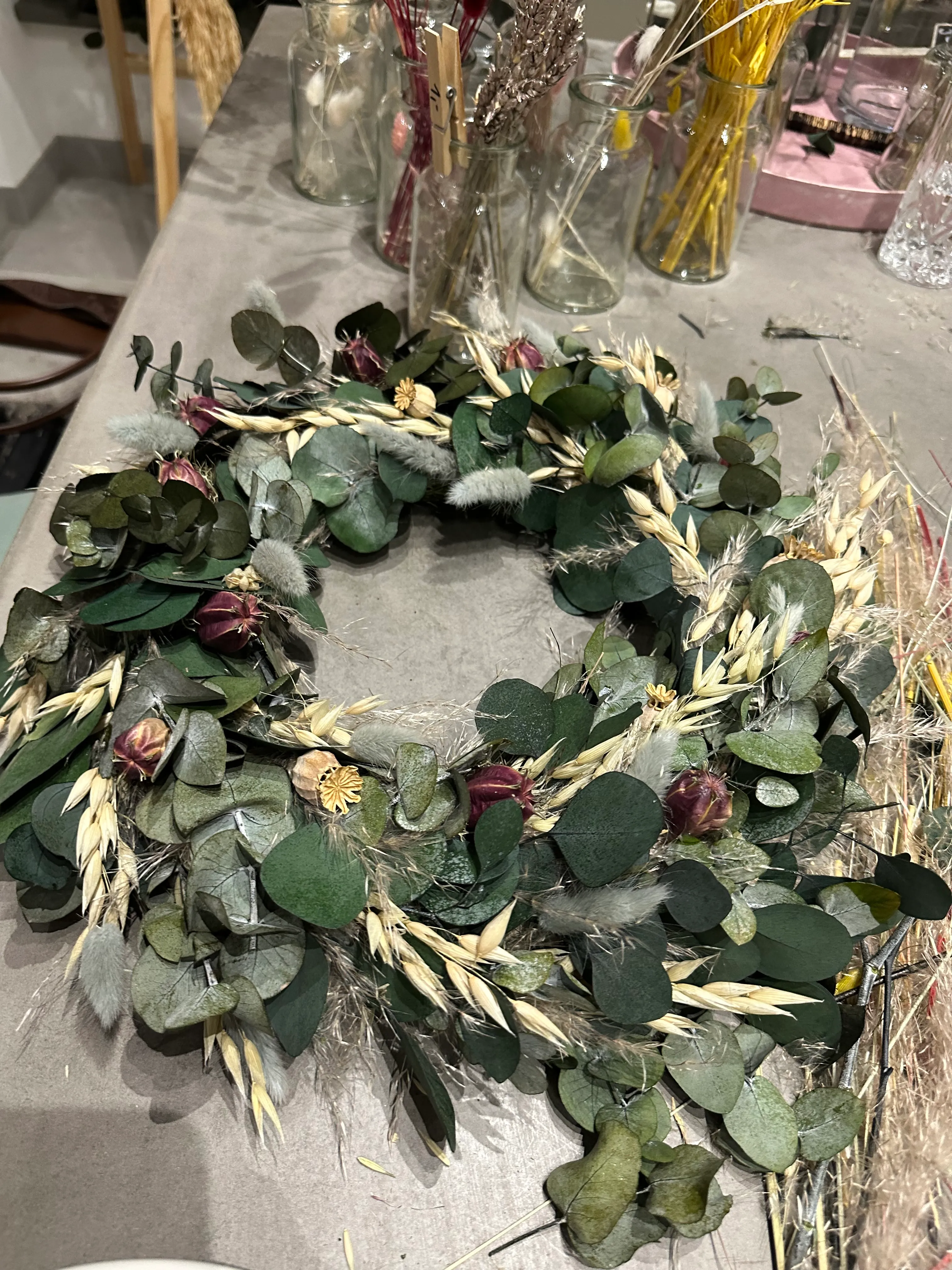 Blumenkranz auf Tisch mit Gläsern.