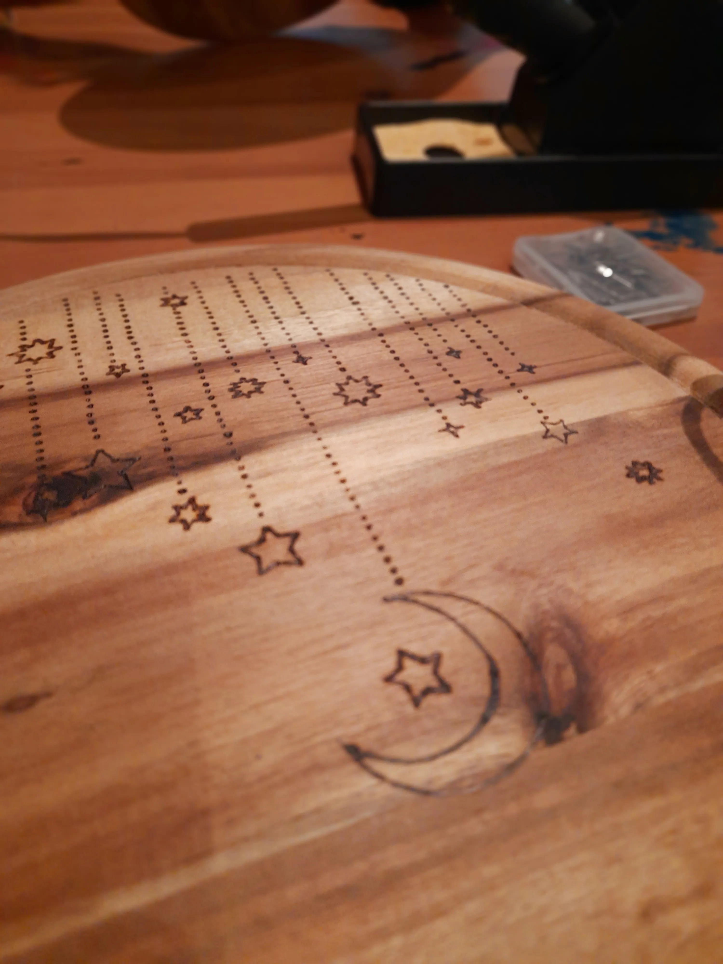 Holzplatte mit Sternen und Mondsicheldesign.