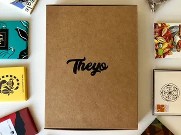 Braune Box liegt auf Tisch, umgeben von Schokoladentafeln.
