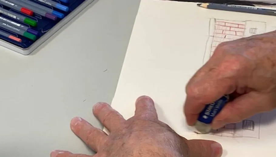 Hands erasing pencil sketch on white paper.