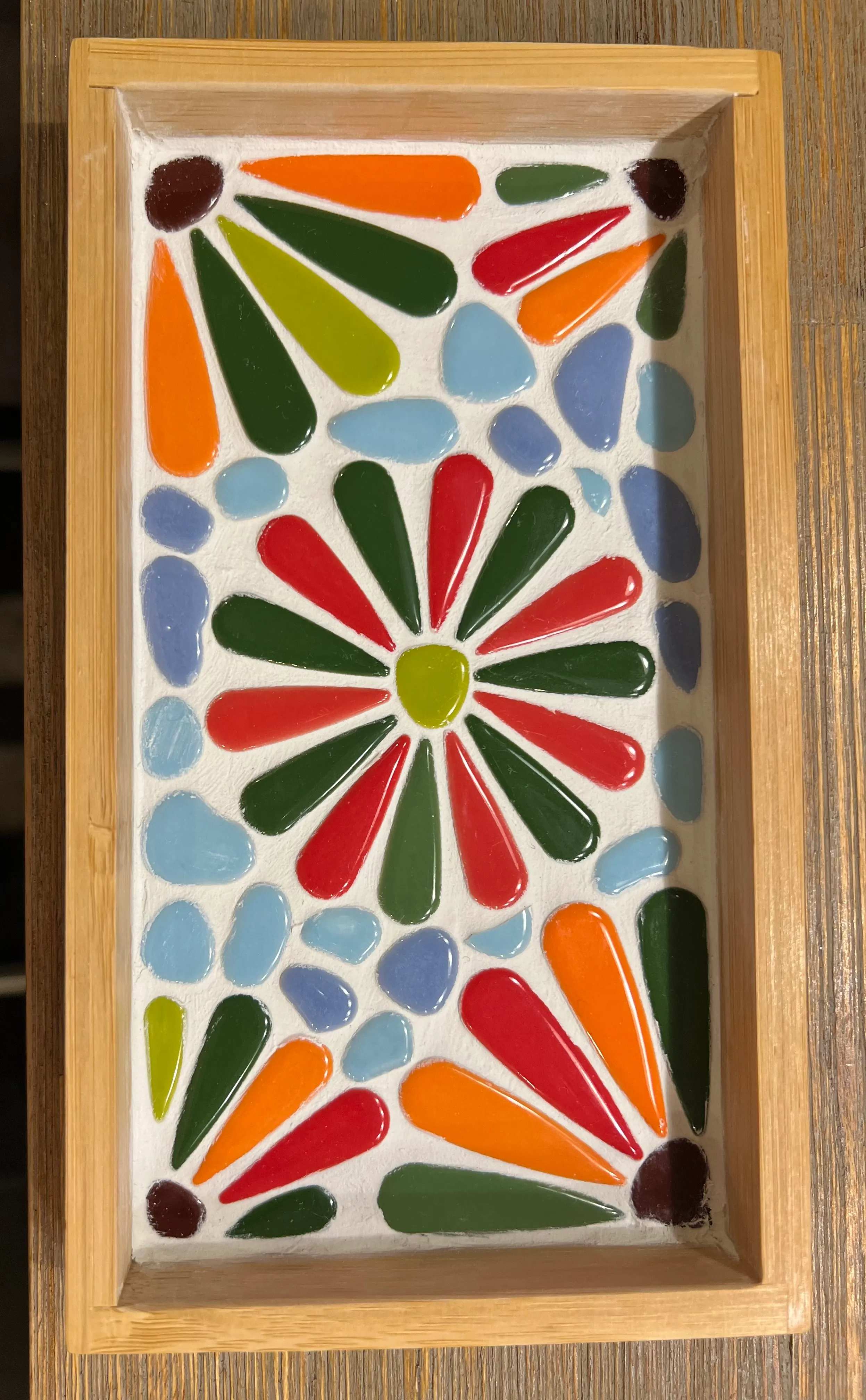 Buntes Mosaikmuster in Holzrahmen.