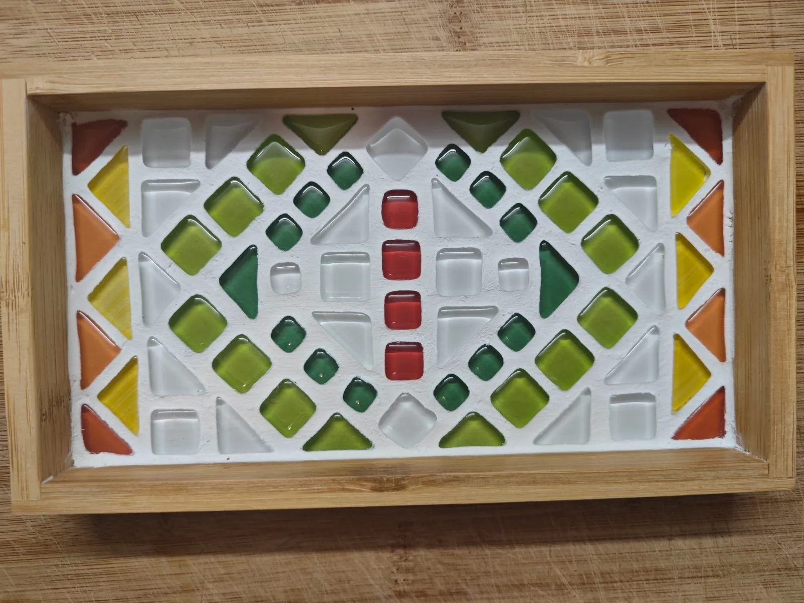 Buntes geometrisches Mosaik im Holzrahmen.