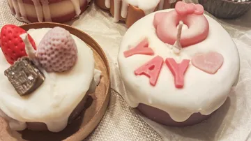 Cupcake-shaped candles with decorations on table.