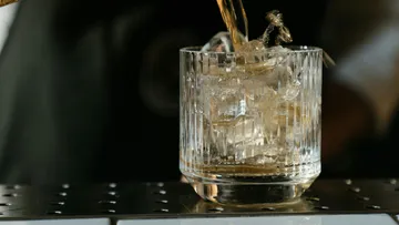 Cocktail being poured into glass with ice.
