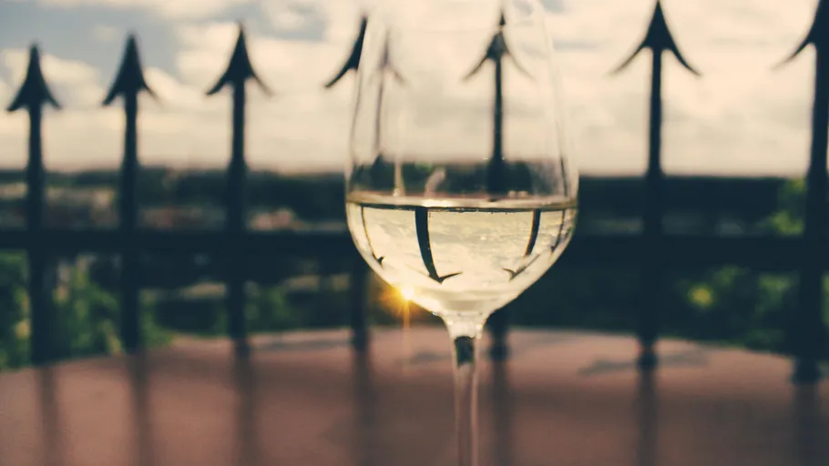 Wine glass on table, outdoor railing background.