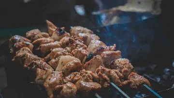 Skewered meat grilling over open flame.