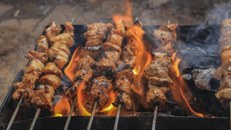 Skewered meat grilling over open flames.