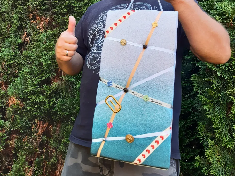 Felt-Tasche mit Dekorationen, gehalten vor einem grünen Hintergrund.
