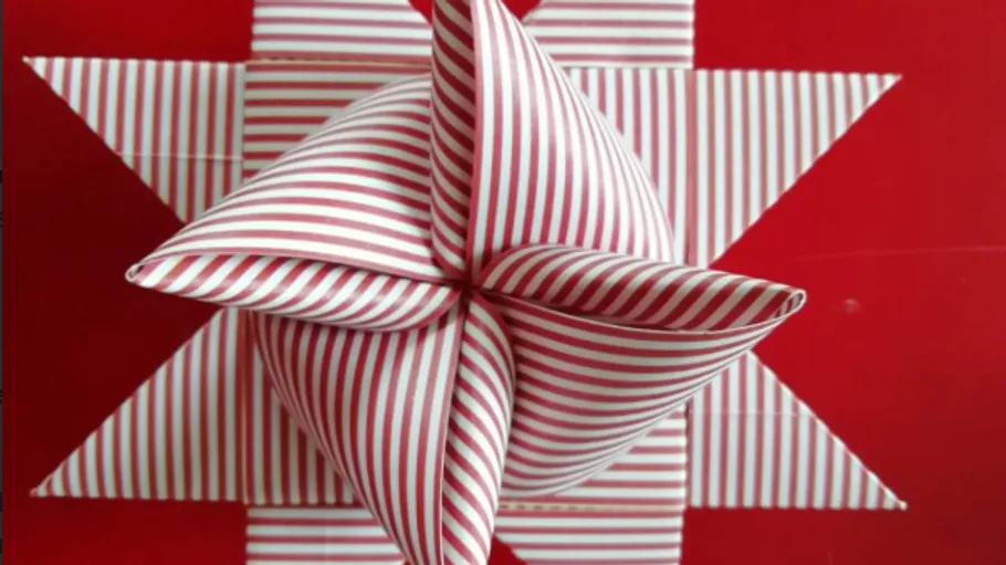 Striped paper star folded on red background.