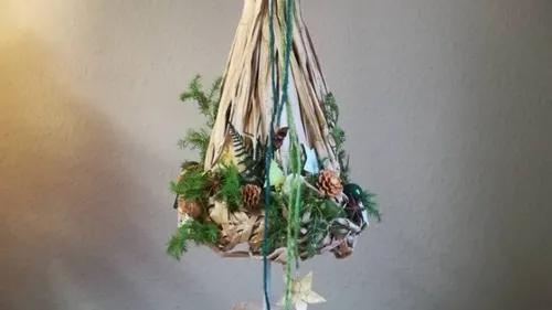 Decorative hanging arrangement with greenery and pinecones.