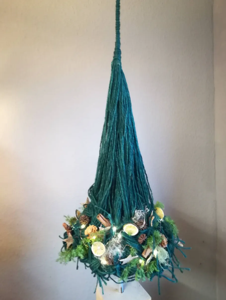 Garn-Weihnachtsbaum mit Dekorationen und Lichtern.