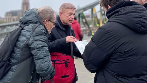 Man showing papers to two people outdoors.