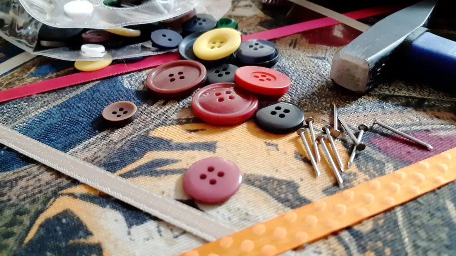 Buttons and nails are strewn around a table.