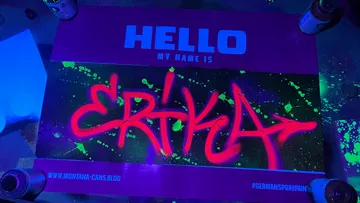 Graffiti name tag under blacklight, neon spray paint.
