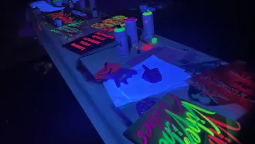 Neon art supplies glowing under blacklight.