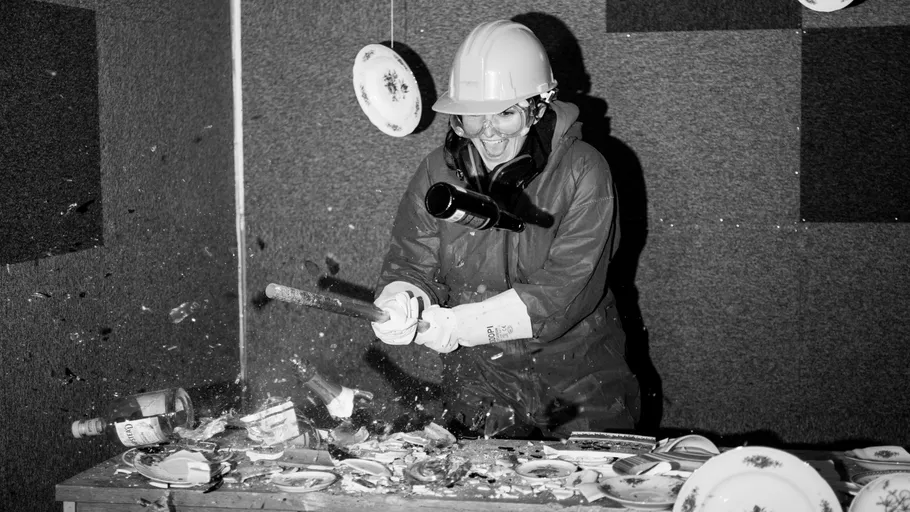 Person smashing plates with a bat indoors.