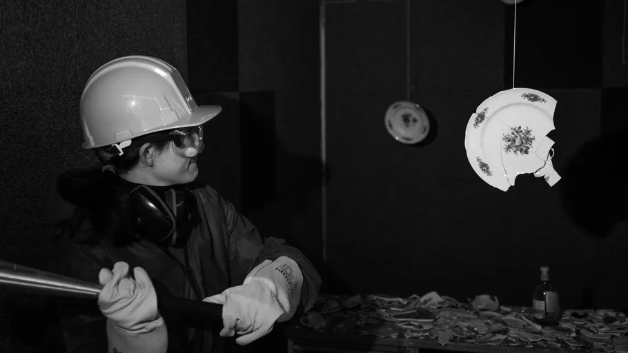 Person in Schutzkleidung schlägt gegen hängenden Teller.