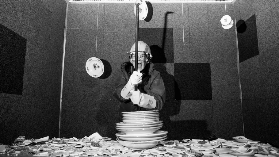 Person zerschlägt Teller in gepolstertem Raum.