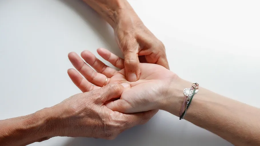 Two hands massaging another hand on table.