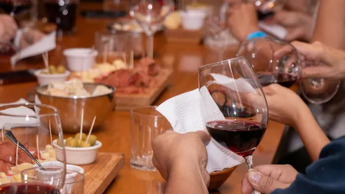 People holding wine glasses at a table.