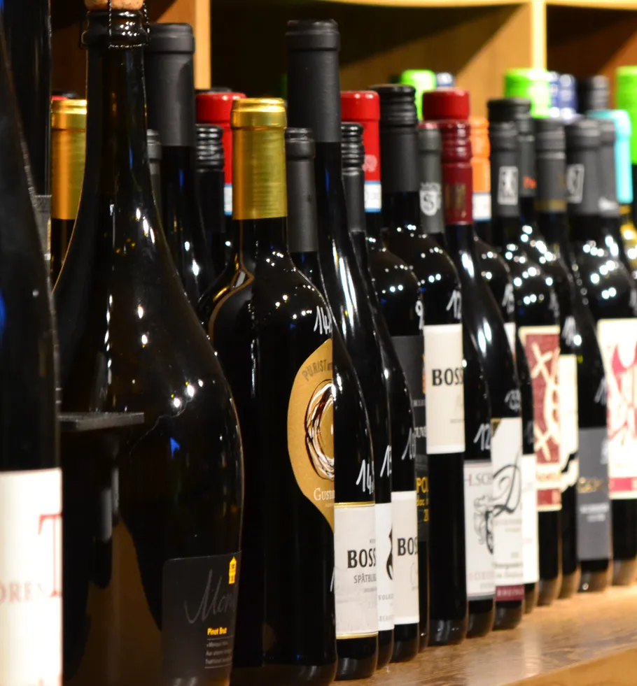 Weinflaschen auf Holzregalen ausgestellt.